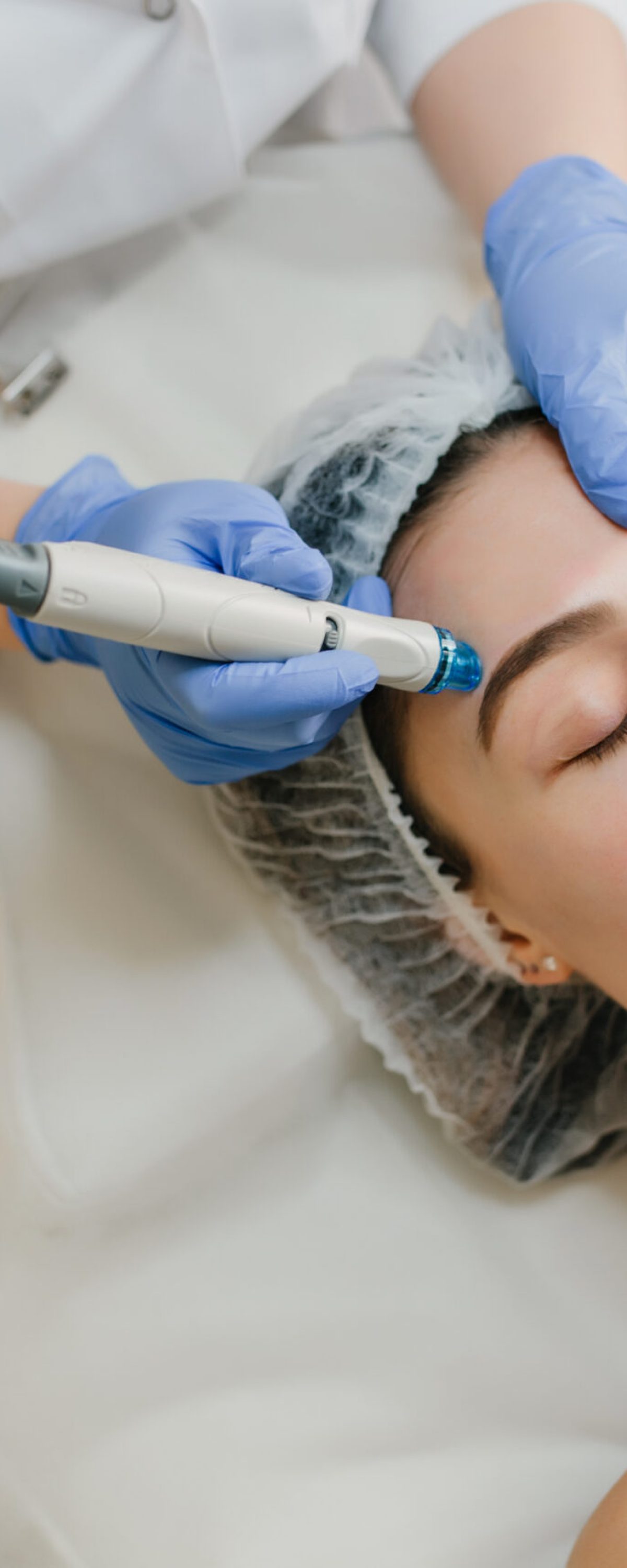 View from above rejuvenation of beautiful woman enjoying cosmetology procedures in beauty salon. Dermatology, hands in blue glows, healthcare, therapy, botox